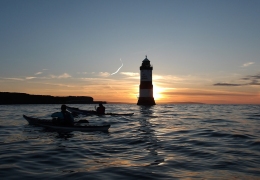 Trwyn Du lighthouse at sunset from the water.